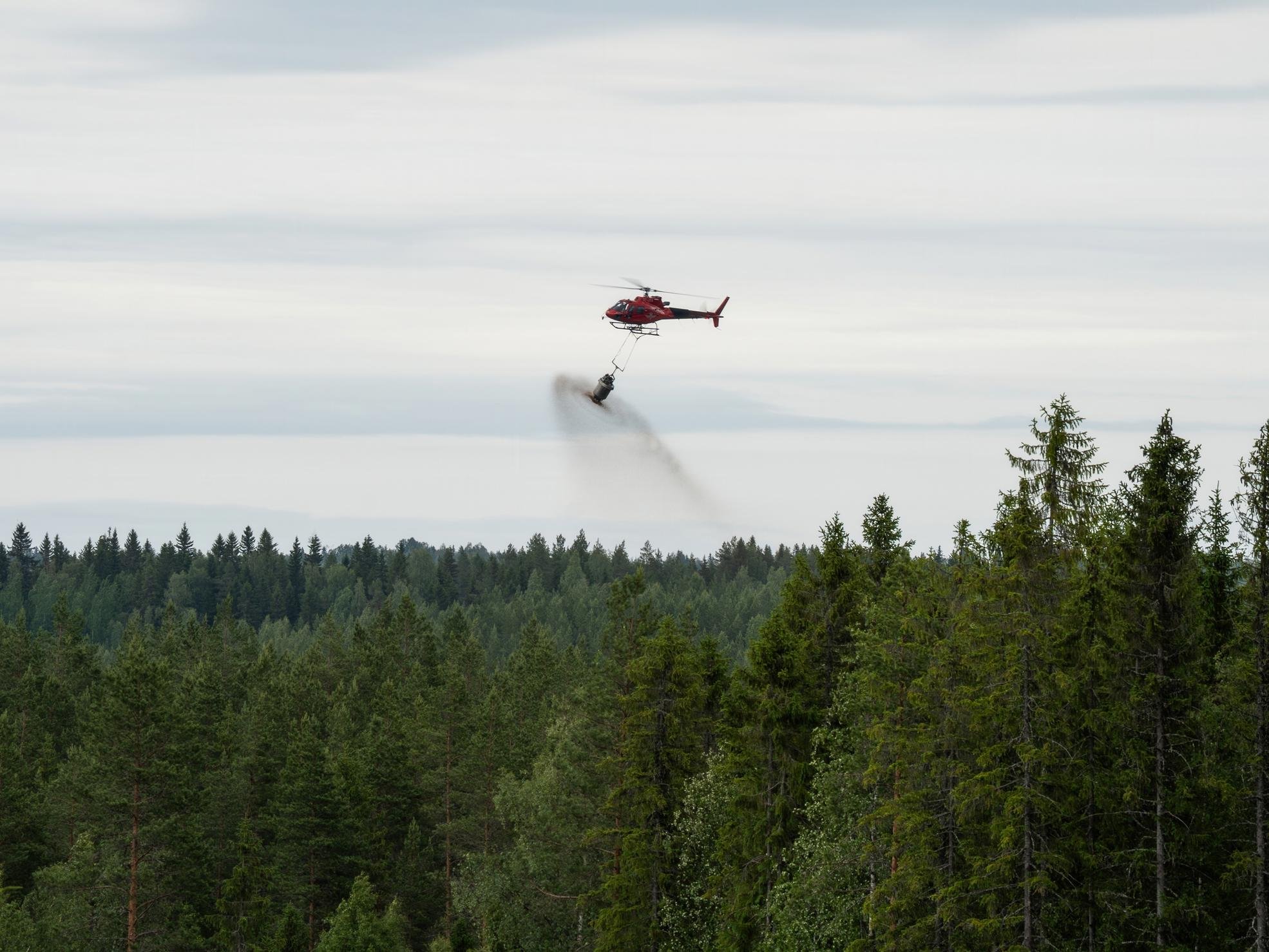 Metsätraktori tyhjentää lannoitesäkkiä levityskoneeseen