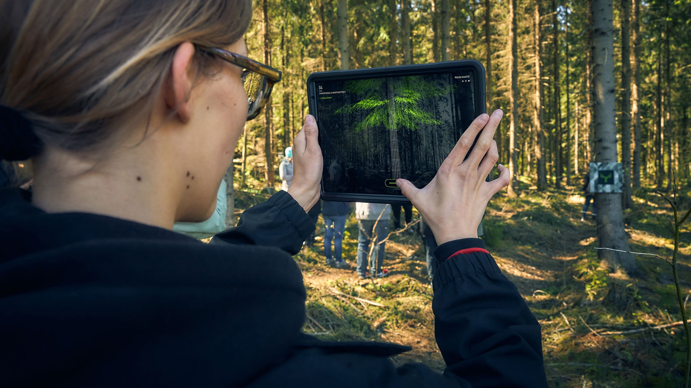 Woman using a tablet for augmented reality experience in the forest