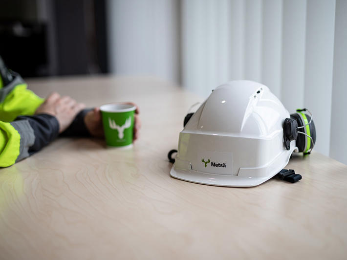 Safety helmet and a cup on coffee on table during a break