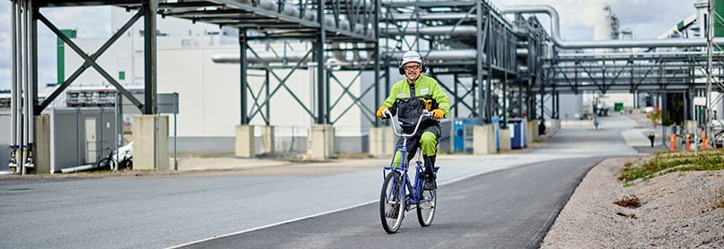 Työntekijä pyöräilee Äänekosken biotuotetehtaan tiellä