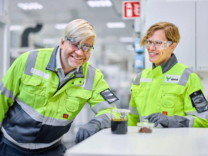 Two people in a laboratory smiling and looking at the new lignin products on the table