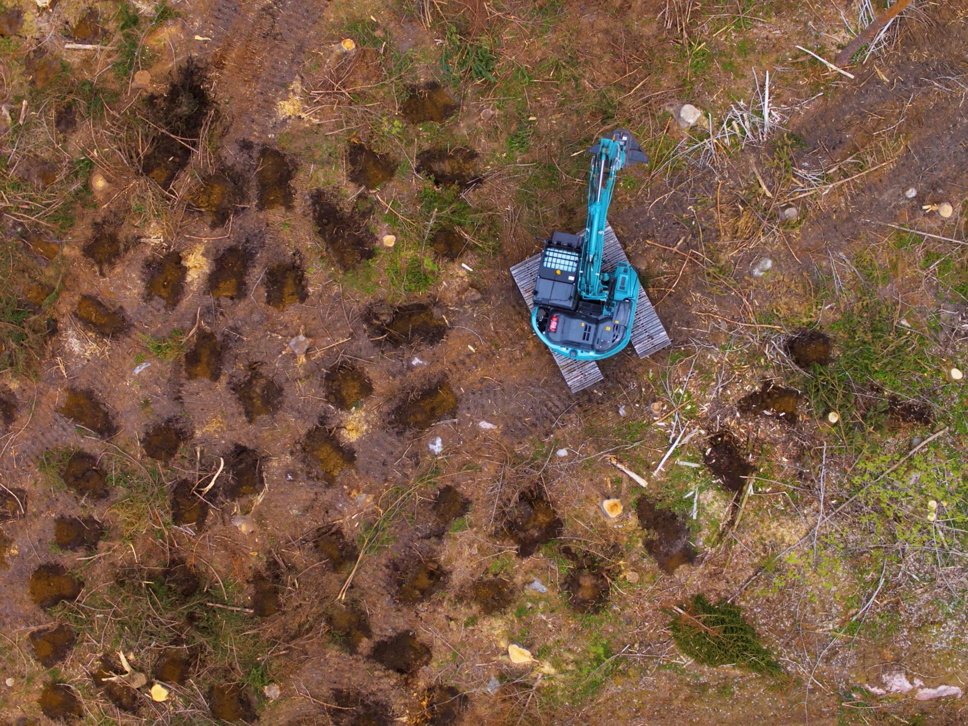 Flygfoto på grävmaskin som utför vändhögläggning.