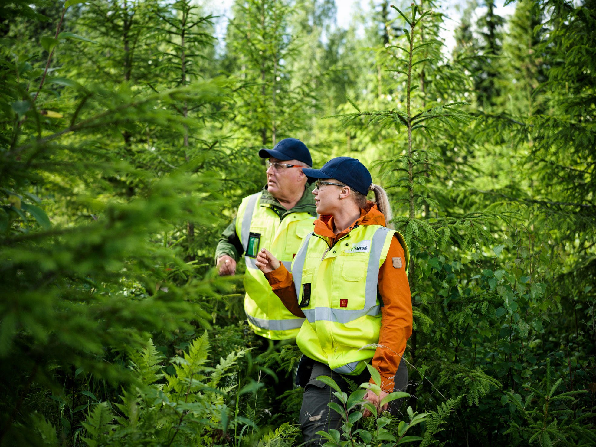 Metsäasiantuntija ja metsänomistaja kävelevät metsässä kohti kameraa.