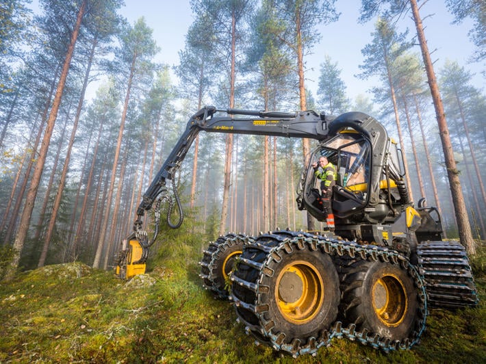 Forest machine and driver standing in front of it.