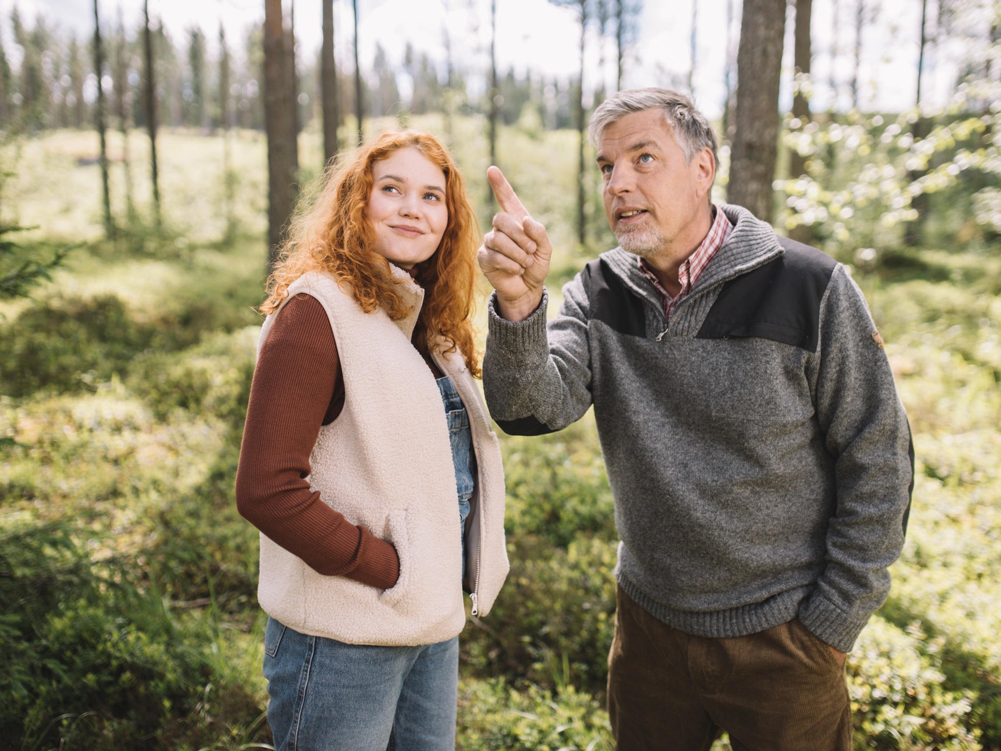 Far och dotter står i skogen och tittar i den riktning dottern pekar.