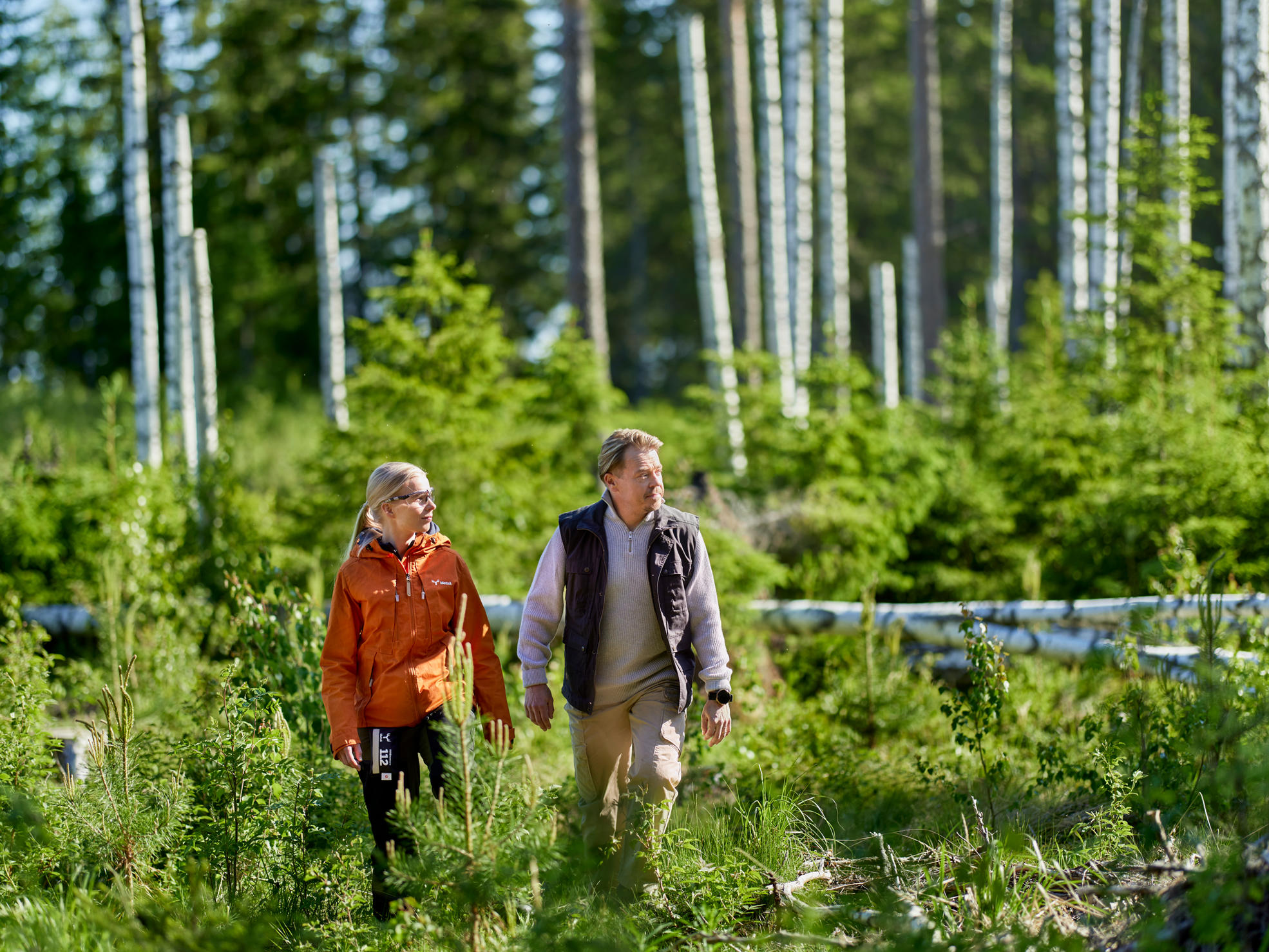 En skogsexpert och en skogsägare i skogen, med en skyddsbusgage i bakgrunden.